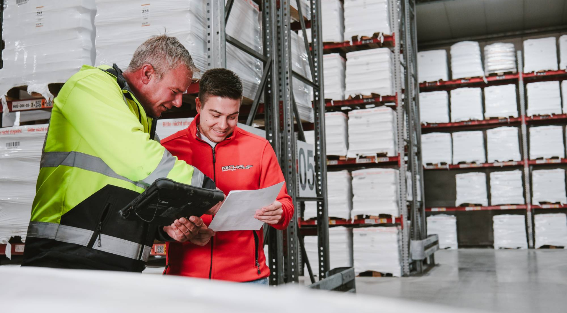 Zwei Mitarbeiter besprechen Dokumente im Lager.