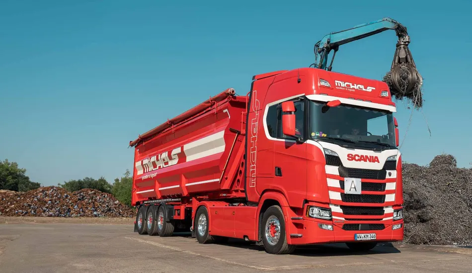 Roter Lkw mit Kran und Mulde.