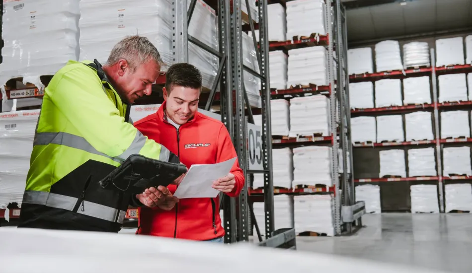 Zwei Mitarbeiter besprechen Dokumente im Lager.